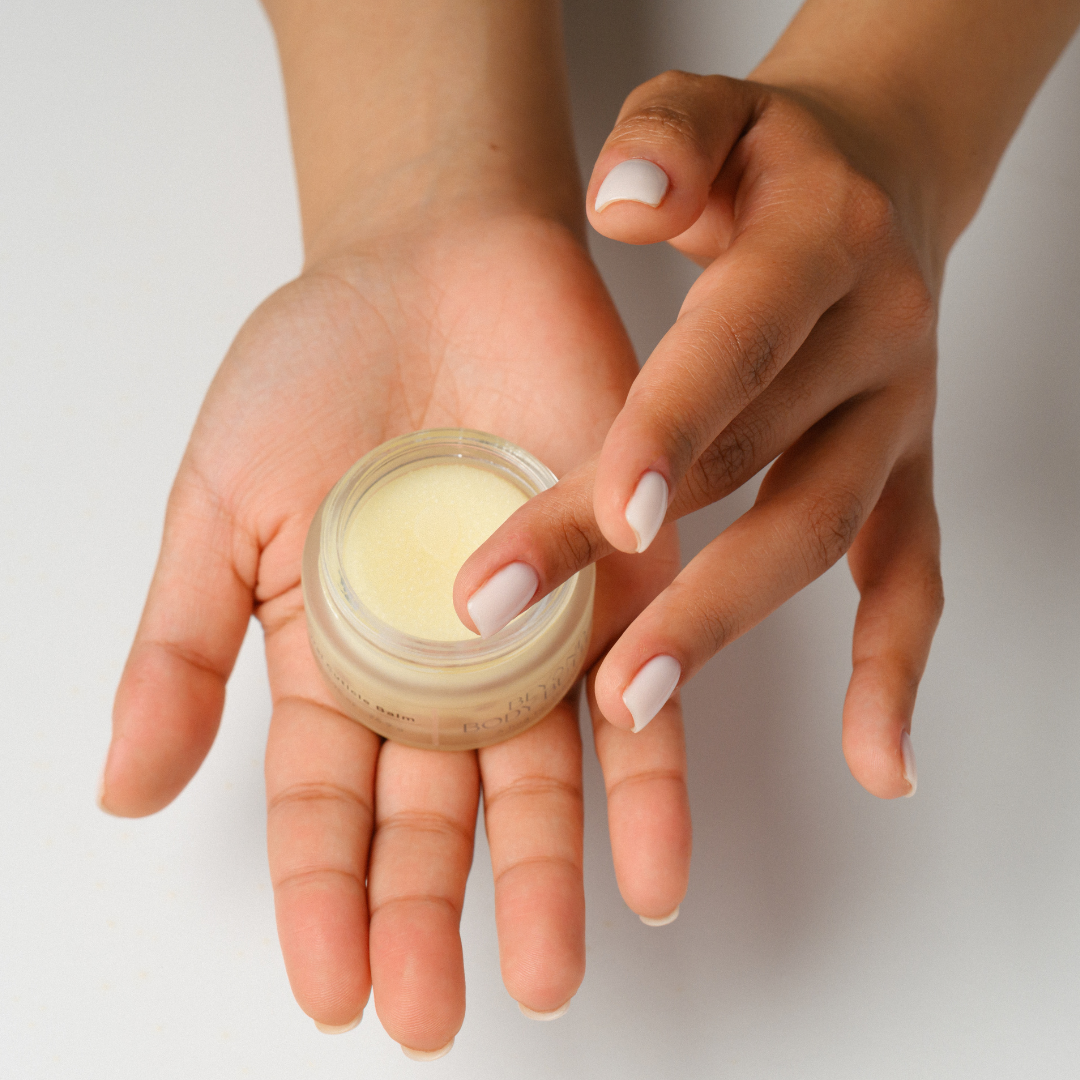 Person holding a small jar of cream in one hand with a neutral background